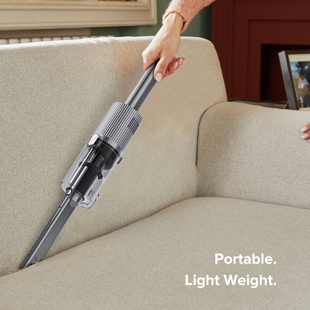 Person using a handheld vacuum cleaner on a beige sofa with text 'Portable. Lightweight.'